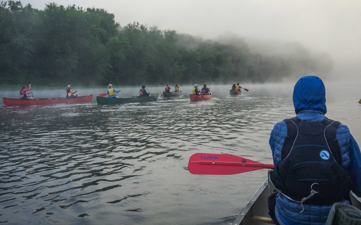 a group of canoes are paddled into fog on an outward bound veterans trip